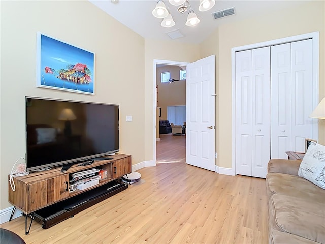 living room featuring baseboards, light wood-style floors, visible vents, and a chandelier