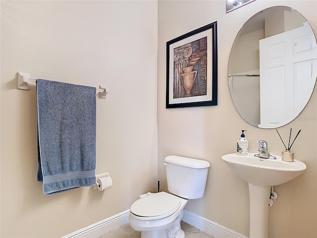 half bathroom with tile patterned floors, toilet, and baseboards