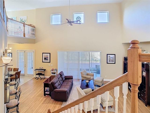 living room with french doors, baseboards, stairway, and light wood finished floors