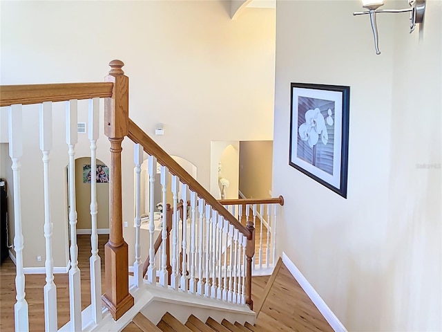 stairs featuring wood finished floors, baseboards, and arched walkways