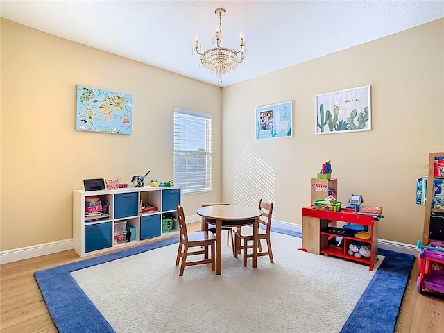 game room with wood finished floors, baseboards, and a chandelier