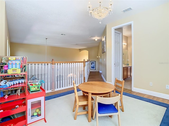 dining space with visible vents, baseboards, an inviting chandelier, and wood finished floors