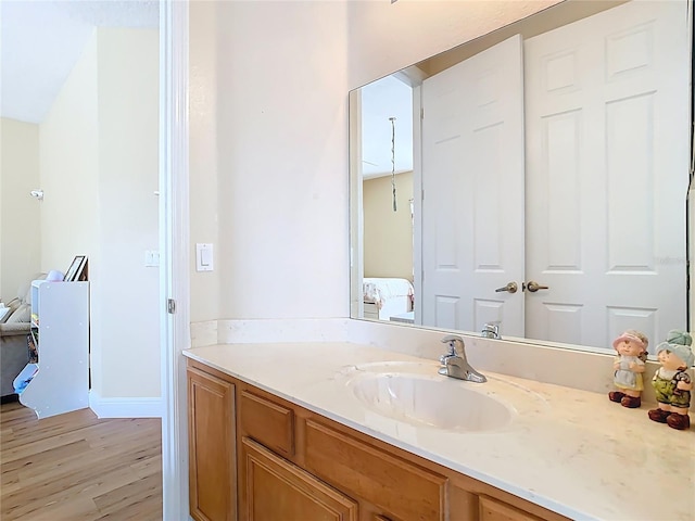 bathroom featuring baseboards, wood finished floors, ensuite bath, and vanity