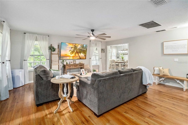 living room featuring visible vents, wood finished floors, and a ceiling fan