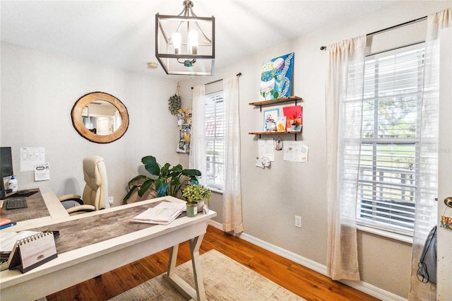 home office with wood finished floors, a healthy amount of sunlight, baseboards, and a chandelier