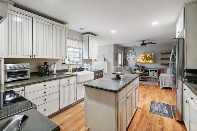 kitchen featuring a sink, dark countertops, light wood-style flooring, and ceiling fan