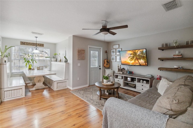 living area with visible vents, a ceiling fan, a textured ceiling, wood finished floors, and baseboards