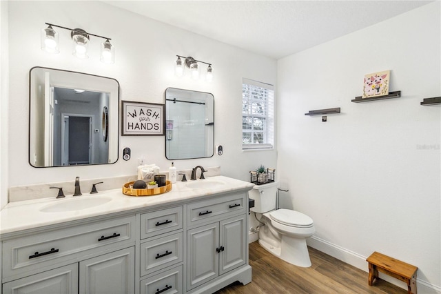 full bath with double vanity, toilet, wood finished floors, and a sink