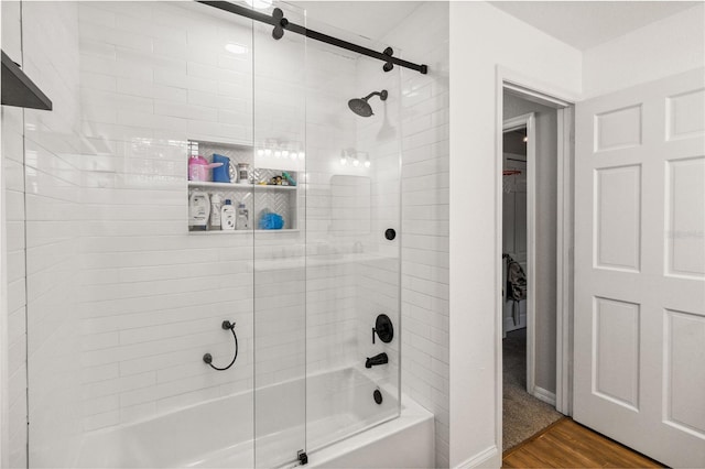 full bathroom with wood finished floors, baseboards, and bath / shower combo with glass door