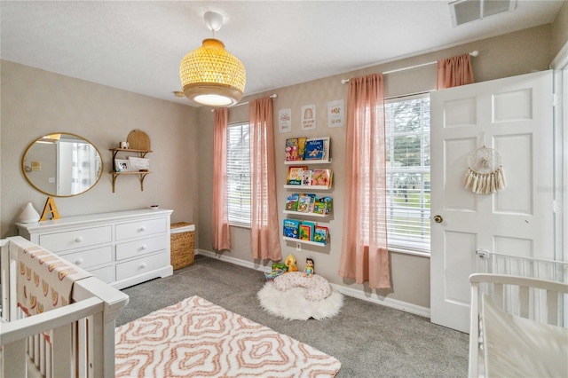 carpeted bedroom featuring visible vents, baseboards, and a nursery area