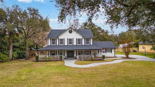 farmhouse-style home featuring covered porch, driveway, a front yard, and roof with shingles