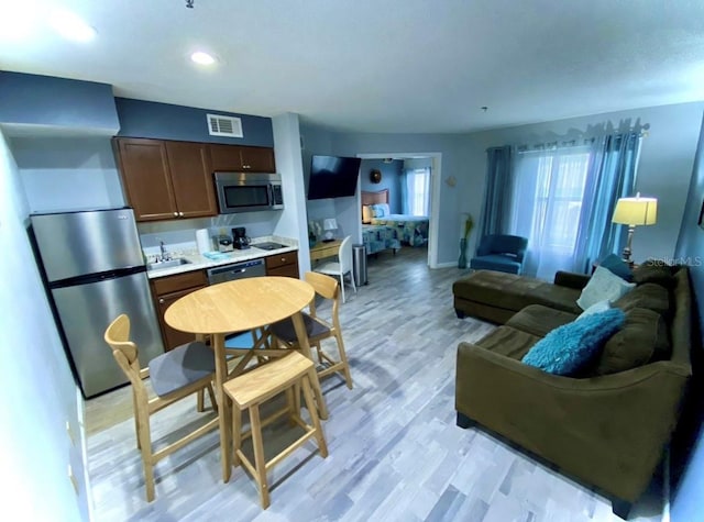 kitchen featuring light wood finished floors, visible vents, light countertops, appliances with stainless steel finishes, and a sink