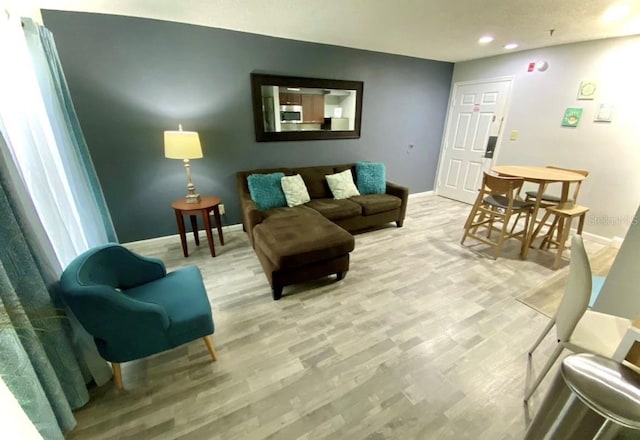 living room featuring recessed lighting, baseboards, and light wood-style floors