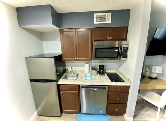 kitchen with visible vents, a sink, a textured ceiling, appliances with stainless steel finishes, and baseboards