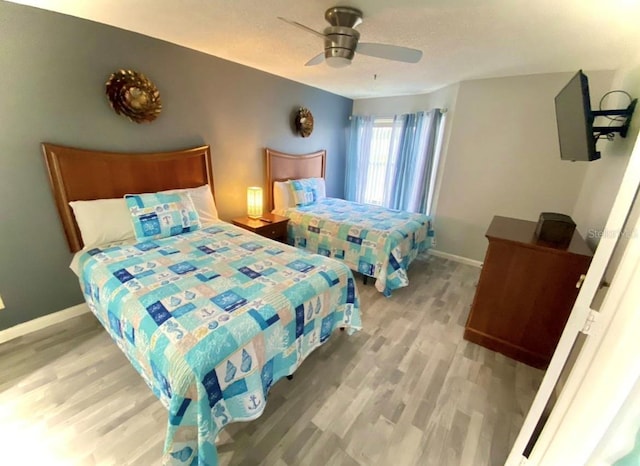 bedroom featuring a ceiling fan, wood finished floors, and baseboards