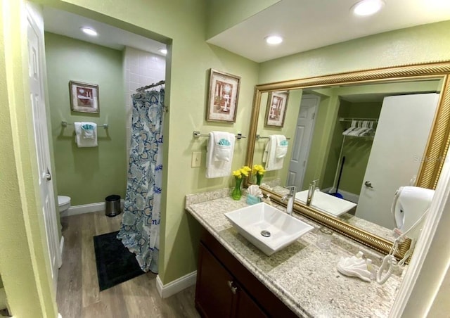 full bath with toilet, vanity, baseboards, and wood finished floors