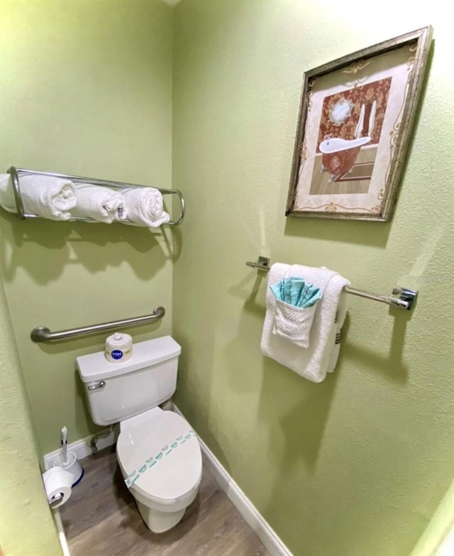 bathroom with baseboards, toilet, and wood finished floors