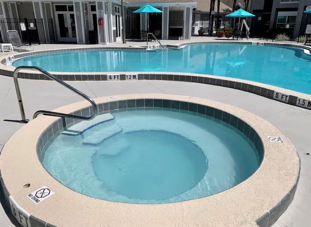 community pool featuring french doors, a hot tub, and a patio