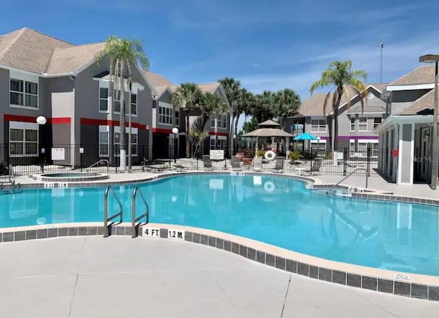 pool featuring a patio, fence, a residential view, and a hot tub