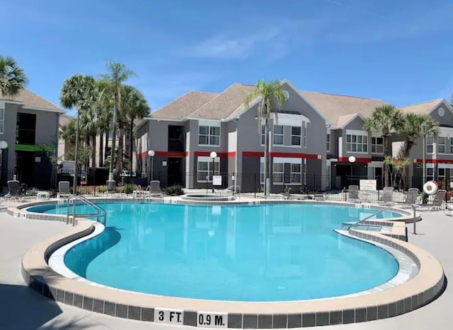 community pool with a residential view, a patio, and fence