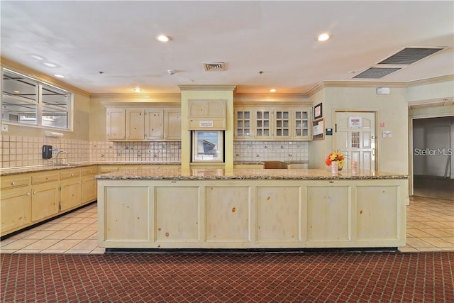 kitchen with tile patterned flooring, visible vents, backsplash, crown molding, and a sink