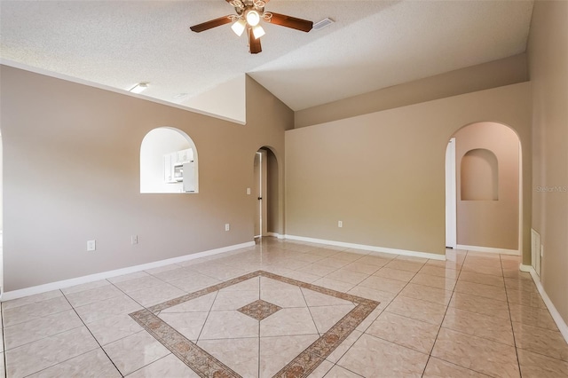 spare room featuring baseboards, arched walkways, and a textured ceiling