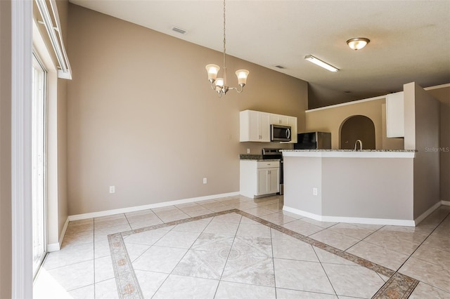 kitchen with a notable chandelier, lofted ceiling, white cabinetry, appliances with stainless steel finishes, and baseboards