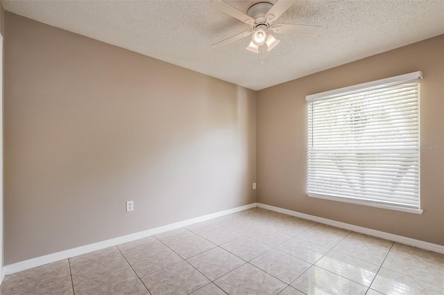 empty room featuring a textured ceiling, light tile patterned floors, baseboards, and ceiling fan