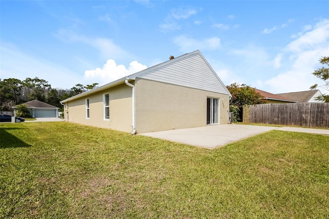 rear view of house featuring a patio, fence, a lawn, and stucco siding