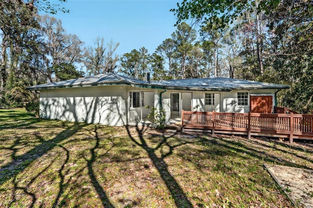 back of house with a wooden deck, metal roof, and a yard