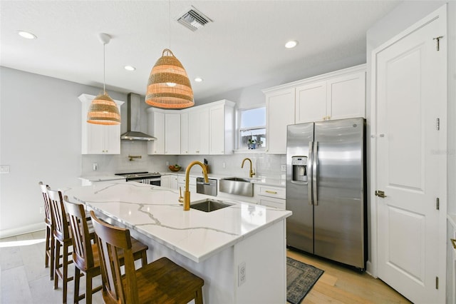 kitchen featuring visible vents, appliances with stainless steel finishes, wall chimney exhaust hood, and decorative backsplash