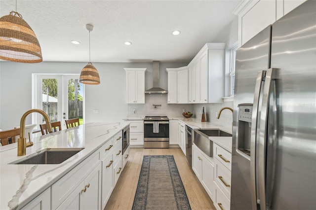 kitchen featuring backsplash, stainless steel appliances, wall chimney range hood, and a sink