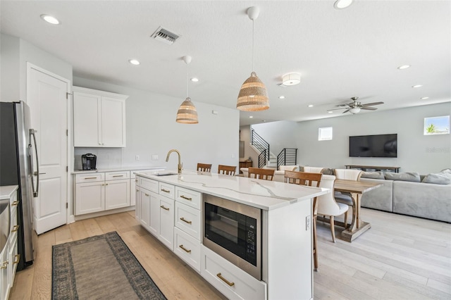 kitchen featuring a sink, built in microwave, a breakfast bar area, and freestanding refrigerator