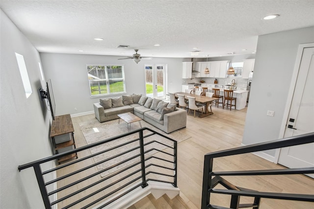 living area featuring ceiling fan, recessed lighting, light wood-style floors, and a textured ceiling