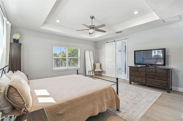 bedroom featuring visible vents, baseboards, light wood finished floors, recessed lighting, and a raised ceiling