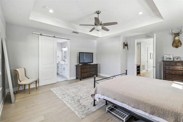 bedroom with visible vents, a raised ceiling, and light wood-style flooring