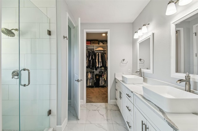 bathroom with a sink, a walk in closet, marble finish floor, and a stall shower