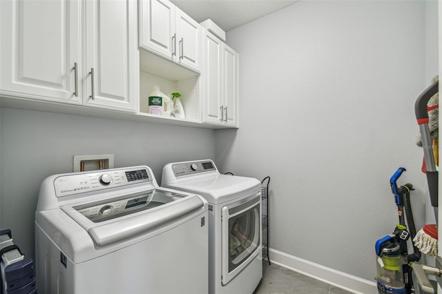 clothes washing area with baseboards, cabinet space, and washing machine and dryer