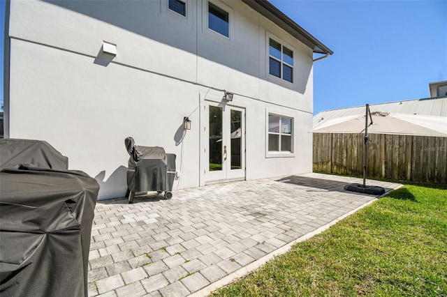 exterior space with a patio, fence, a yard, stucco siding, and french doors