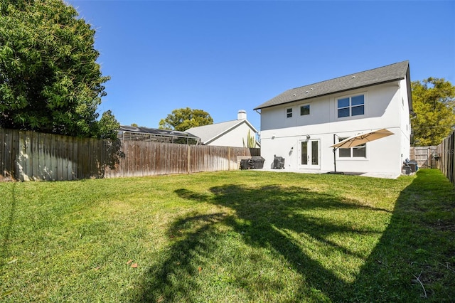 rear view of property with stucco siding, a fenced backyard, french doors, a yard, and a patio area