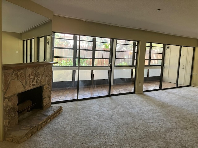 unfurnished living room with a stone fireplace and carpet