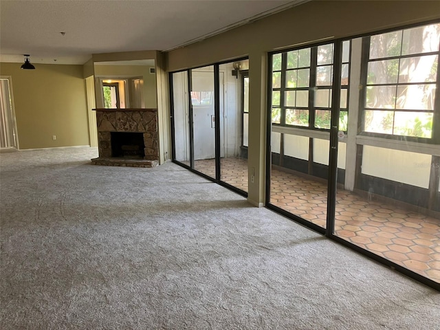 unfurnished living room featuring a stone fireplace and carpet flooring