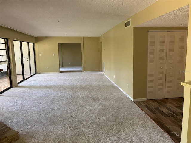 unfurnished room with visible vents, baseboards, a textured ceiling, and wood finished floors