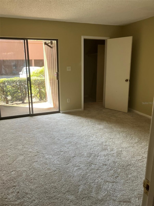 unfurnished bedroom featuring baseboards, carpet, access to exterior, and a textured ceiling