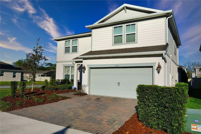 traditional home with a garage, decorative driveway, and board and batten siding