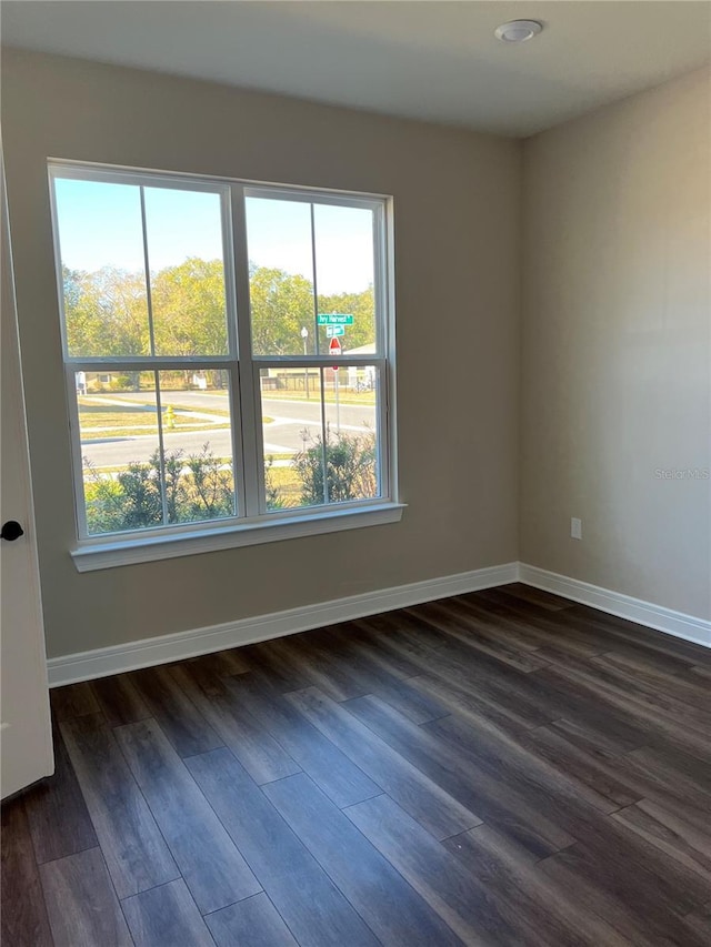 unfurnished room featuring dark wood-type flooring and baseboards