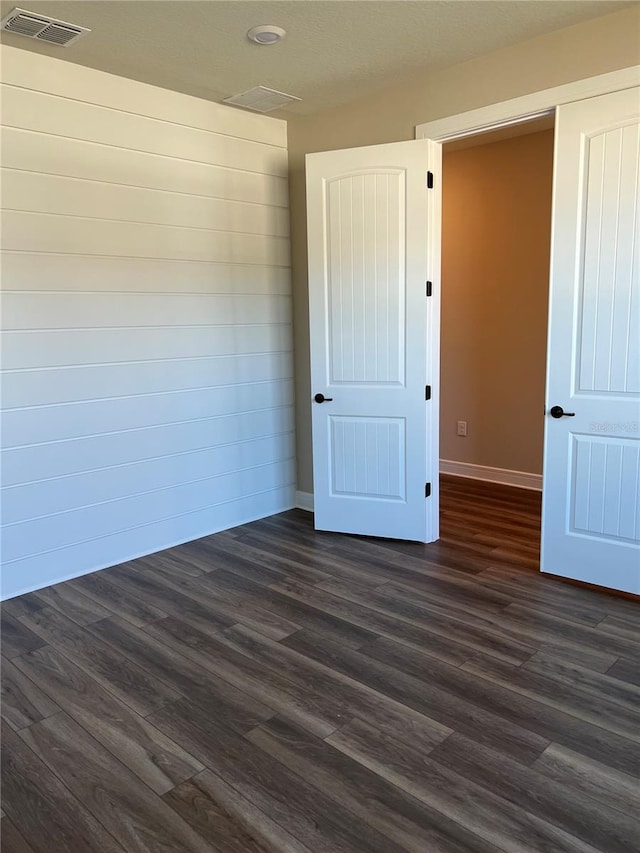 spare room with dark wood finished floors, baseboards, and visible vents