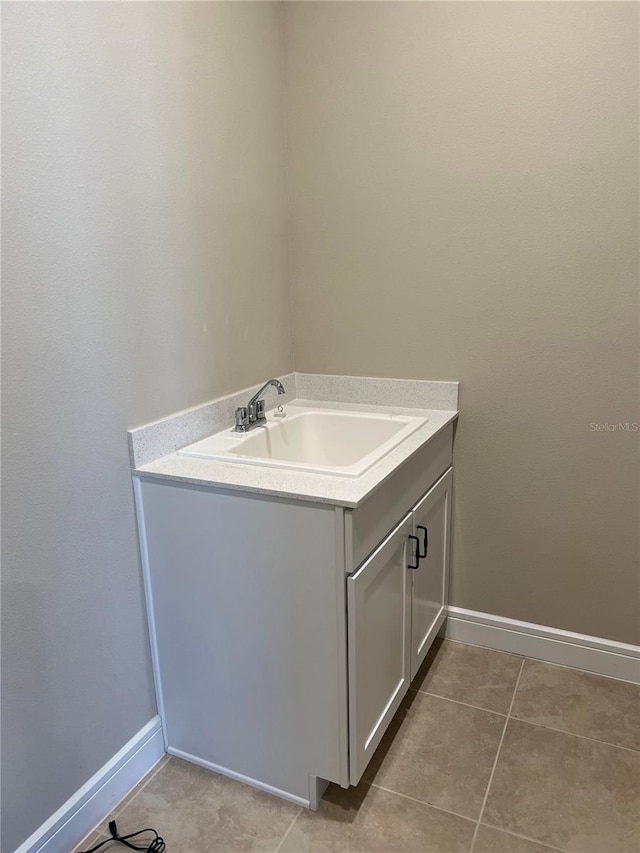 laundry room featuring light tile patterned floors, baseboards, and a sink