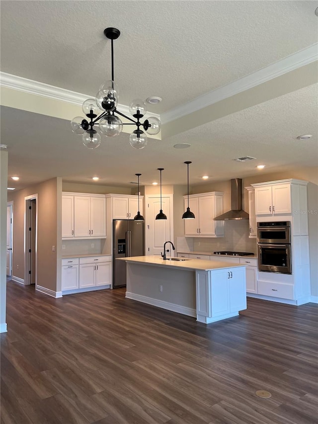 kitchen with dark wood-style flooring, a sink, white cabinets, appliances with stainless steel finishes, and wall chimney range hood