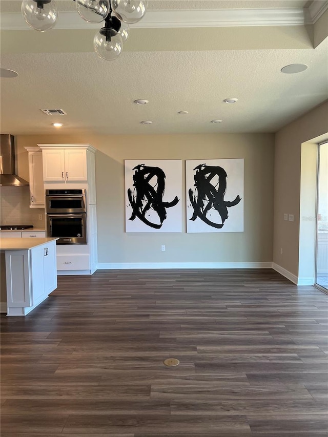 unfurnished living room featuring visible vents, baseboards, a textured ceiling, and dark wood-style flooring